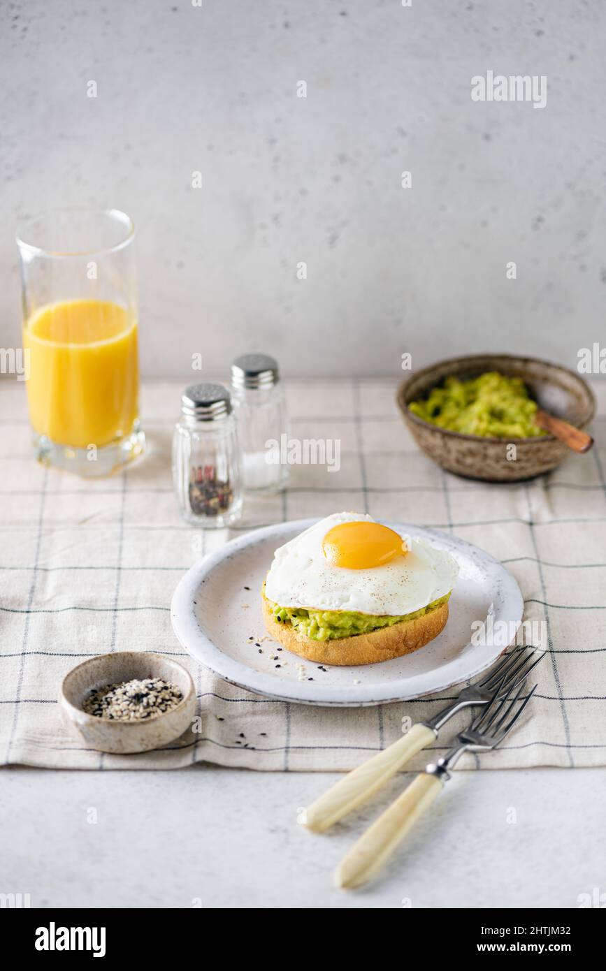 Toast per la colazione con avocado e uova al sole. Colazione sana con toast all'avocado e succo d'arancia Foto Stock