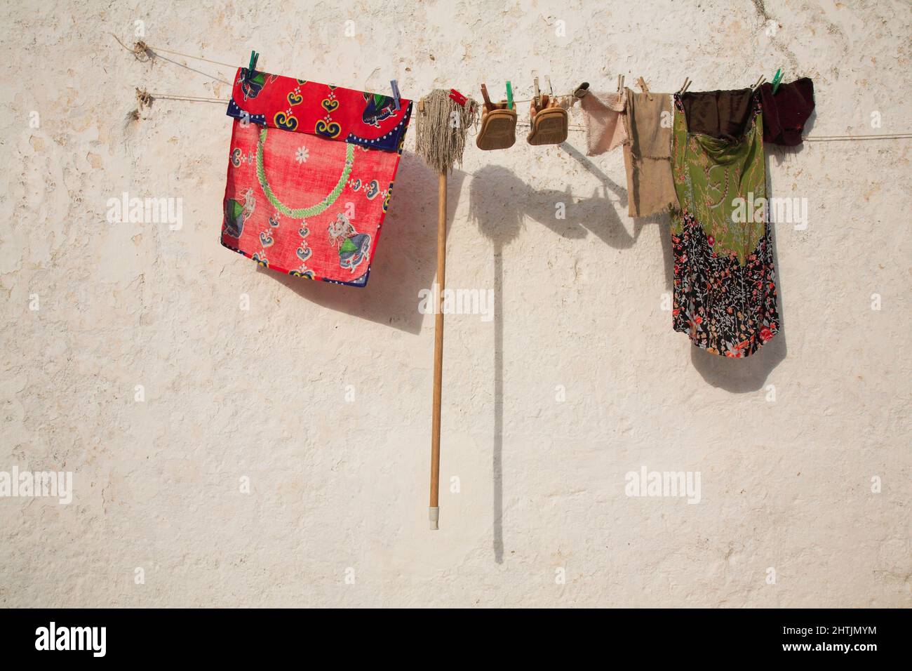 Auf einer Wäscheleine hängen Kleidung, Schuhe und ein Wichmop zum TrocknenSilves, Algarve, Portogallo Foto Stock