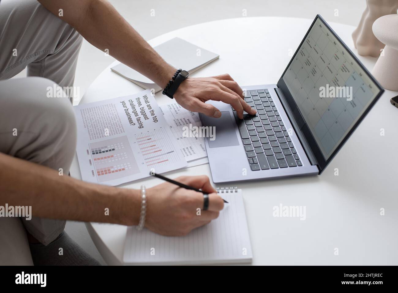 Mano di un giovane auditor maschio o analista che guarda attraverso il documento sullo schermo del laptop mentre si preme uno dei tasti della tastiera Foto Stock
