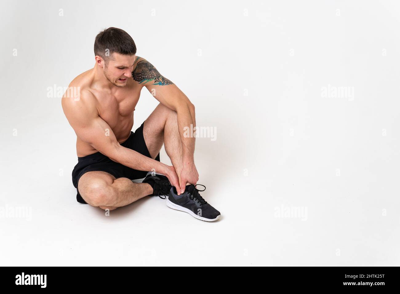 La ginocchia di un uomo fa male su uno sfondo bianco mal doloroso, male maschio giovane stress, presa umana. Tensione mal di collo, inferiore soffrire attraente Foto Stock