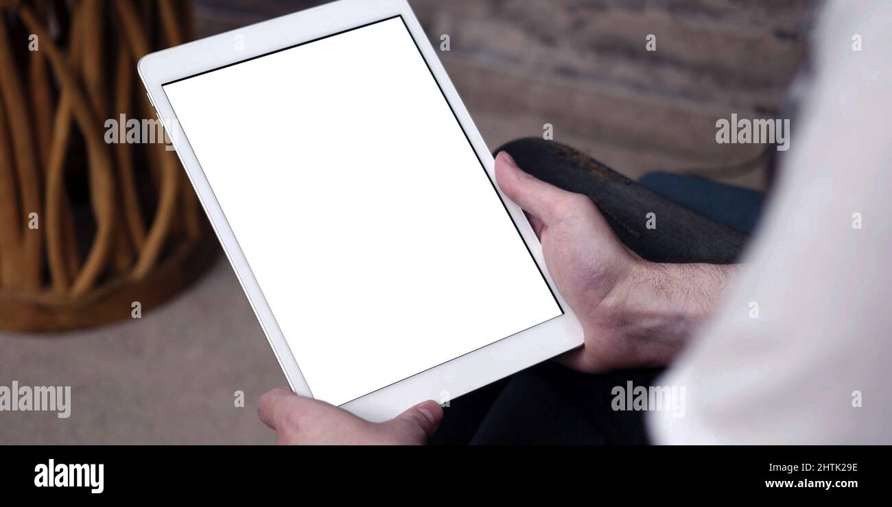 Un tablet con schermo bianco vuoto, ravvicinato sulle mani dell'uomo mentre utilizzi un iPad Apple con touch screen vuoto. Foto Stock