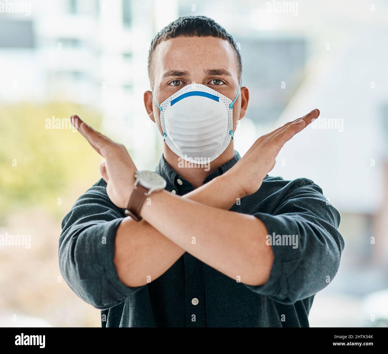 Non oggi, Covid-19. Ritratto di un giovane uomo d'affari che indossa una maschera e che attraversa le braccia in un ufficio moderno. Foto Stock