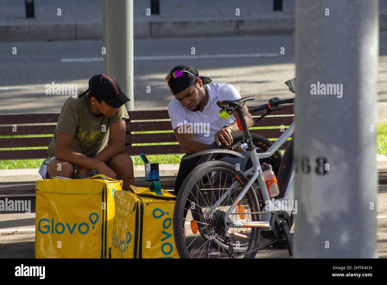 BARCELLONA, SPAGNA - 4 OTTOBRE 2019 due ciclista di consegna seduti su una panchina del parco in conversazione Foto Stock