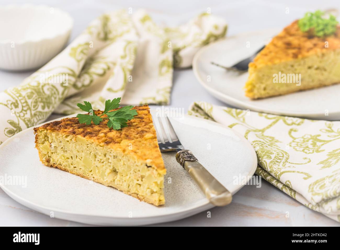 Due pezzi di una torta di patate, tortilla spagnola, frittata, su sfondo bianco Foto Stock