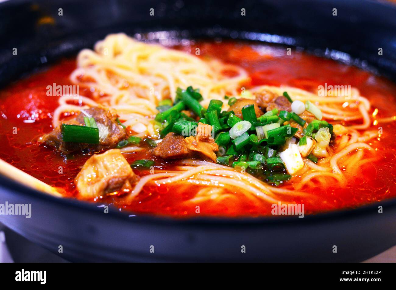 Primo piano di zuppa cinese di noodle di pomodoro con manzo e cipolline tritate sulla parte superiore. Foto Stock