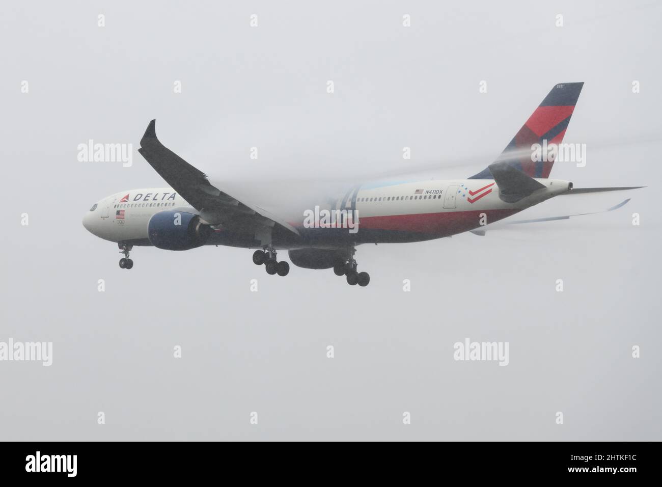 SeaTac, WA, USA - 28 febbraio 2022; Delta Air Lines Airbus A330-900 nel Team USA livrea atterraggio in maltempo con wake Vortex visble dietro l'ala Foto Stock