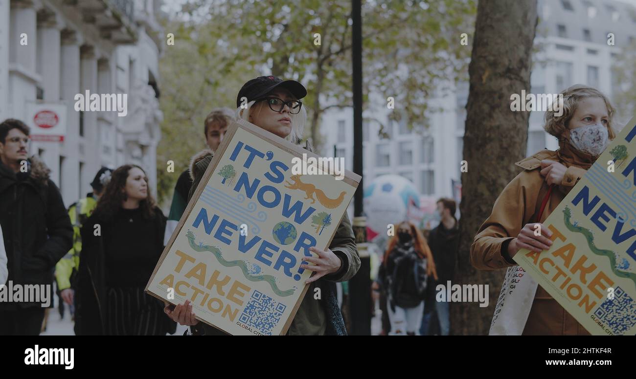Londra, UK - 11 06 2021: Una donna attivista che cammina con un cartello “e’ ora o mai. Take Action” al COP26 “Giornata globale d’azione per la giustizia climatica”. Foto Stock