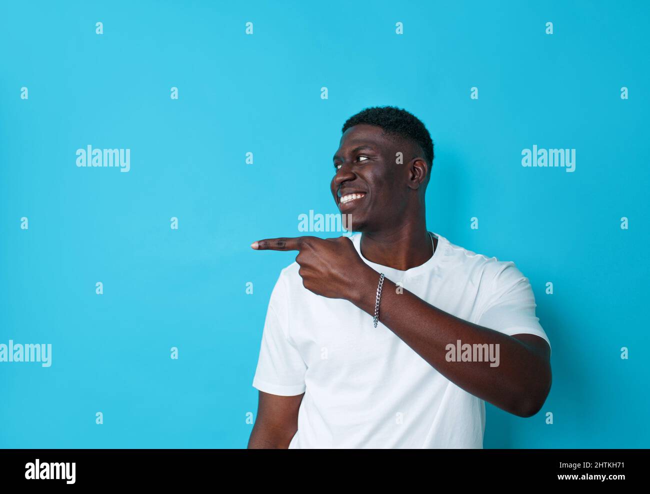 Afroamericano che punta il fianco con il dito su uno sfondo blu isolato Foto Stock