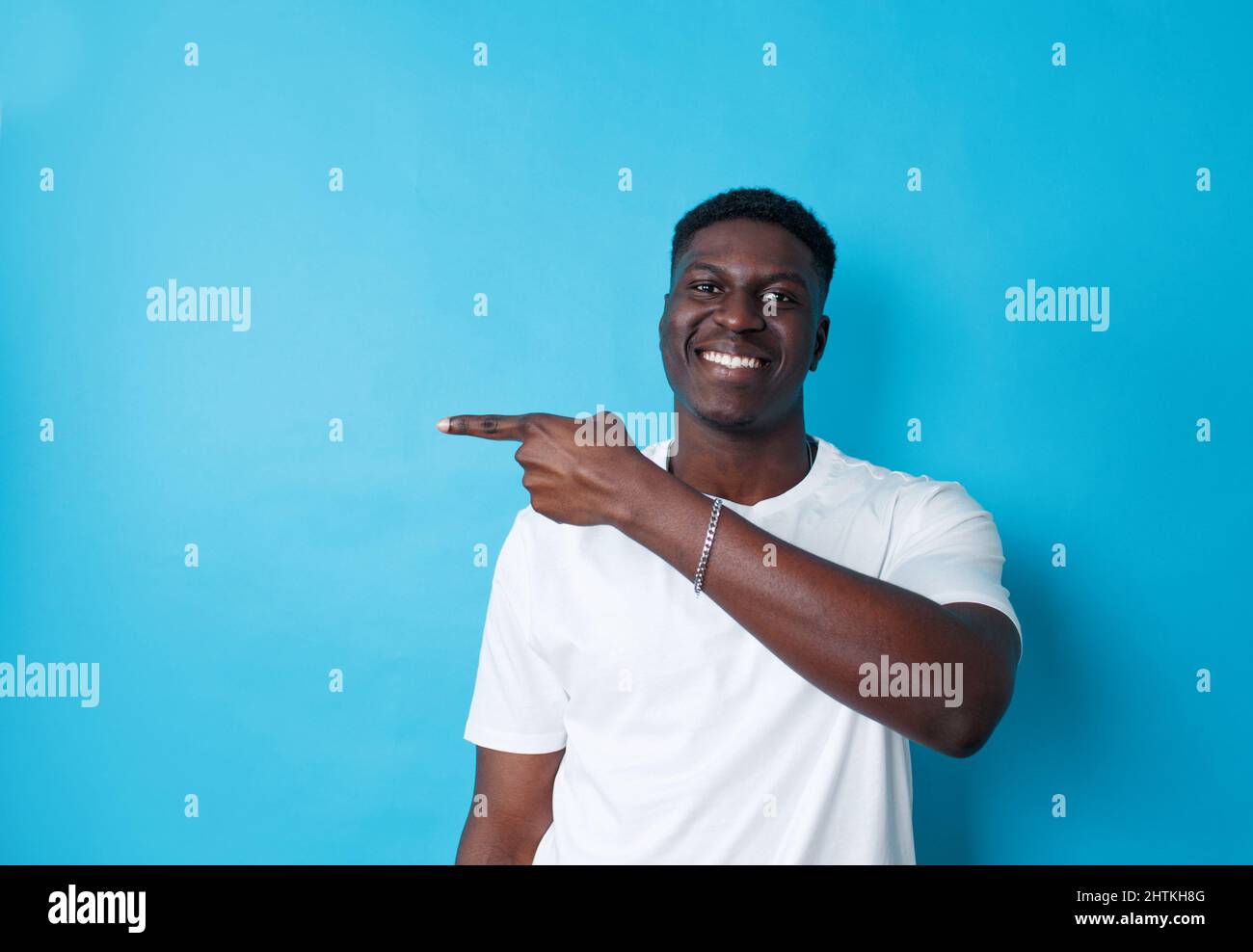 Afroamericano che punta il fianco con il dito su uno sfondo blu isolato Foto Stock