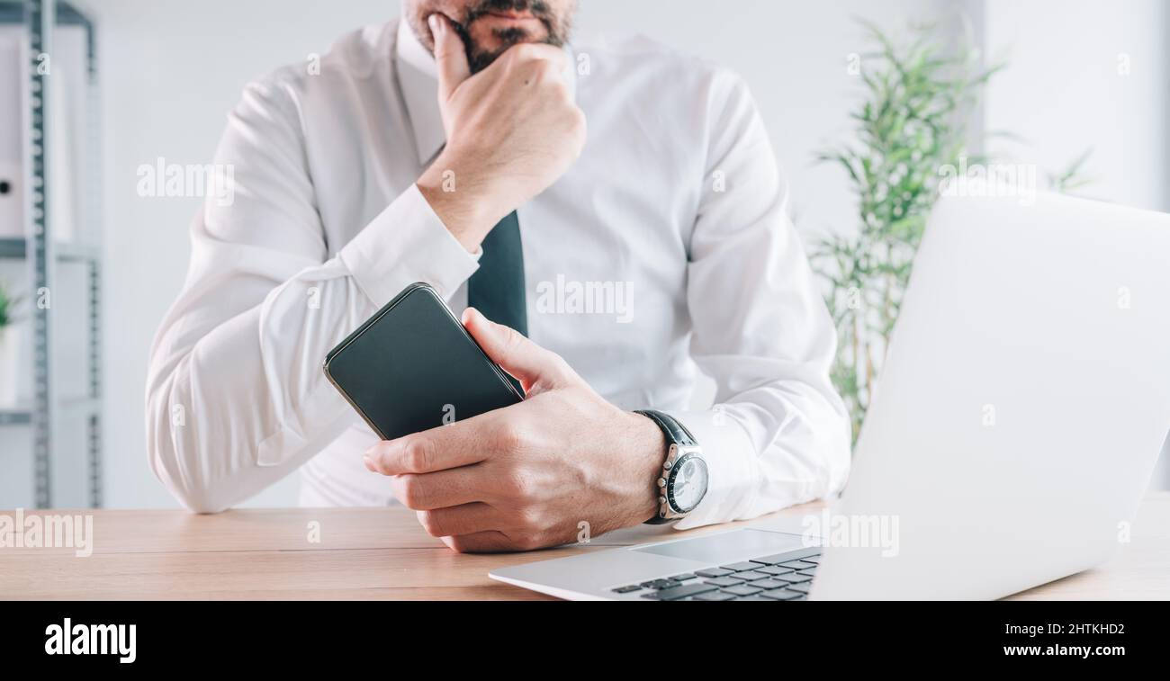 Importanza della tecnologia moderna nel commercio, imprenditore che posano con il telefono mobile intelligente ed il calcolatore del laptop in ufficio, fuoco selettivo Foto Stock