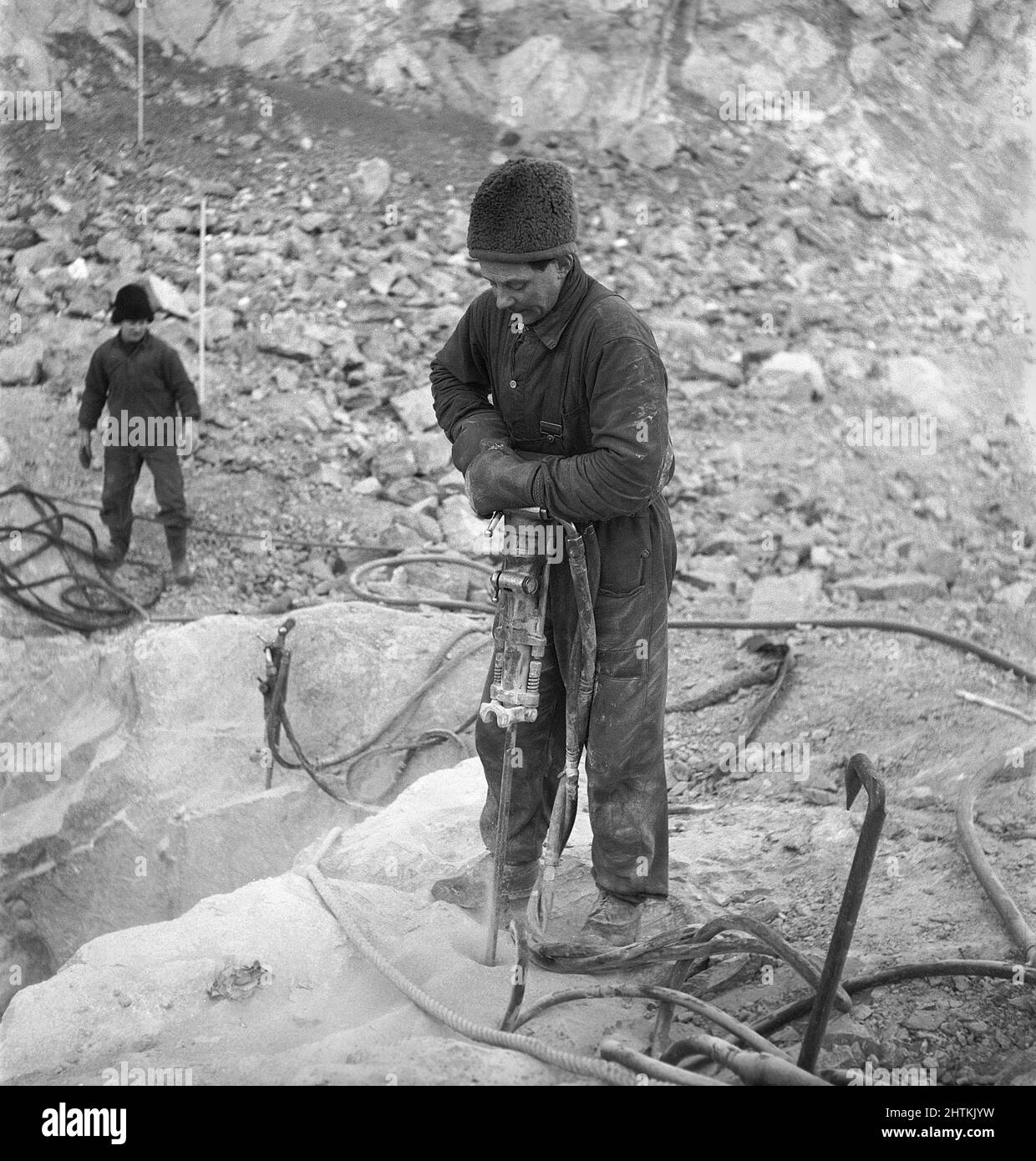 Kiruna Svezia nel 1950s. La miniera aperta e i lavoratori che perforano fori per mettere esplosivi in. Il trapano è alimentato da aria compressa e il rumore sarebbe stato molto alto, ma l'uomo che lavora con esso sembra non notare il suono anche senza indossare alcuna protezione per le orecchie. Potrebbe già avere un'audizione così brutta che il problema del rumore alto non è un problema. Svezia 1954 Kristoffersson BP23-5 Foto Stock