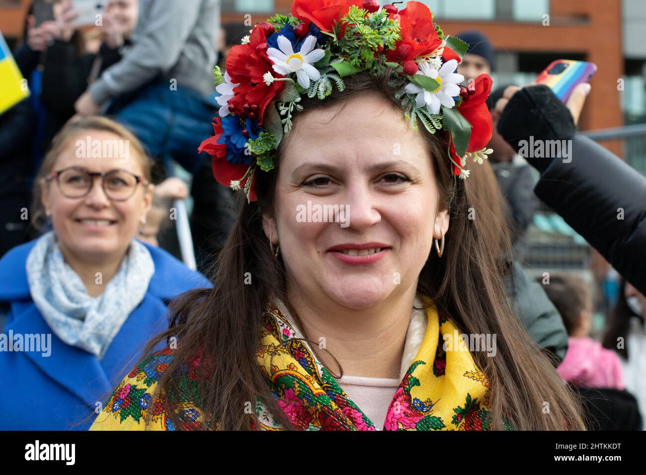 Stand con Ucraina protesta, Piccadilly Gardens, Manchester UK. Donna con abito tradizionale Ukranian con testa floreale Foto Stock