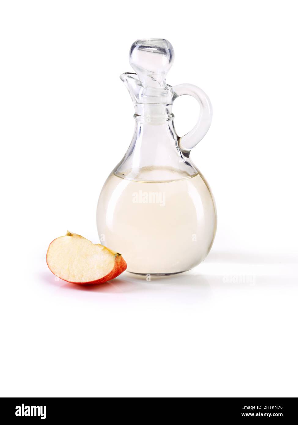 Aceto di sidro di mele - così tanti grandi benefici per la salute. Da studio una brocca di aceto di sidro di mele con una fetta di mela accanto. Foto Stock