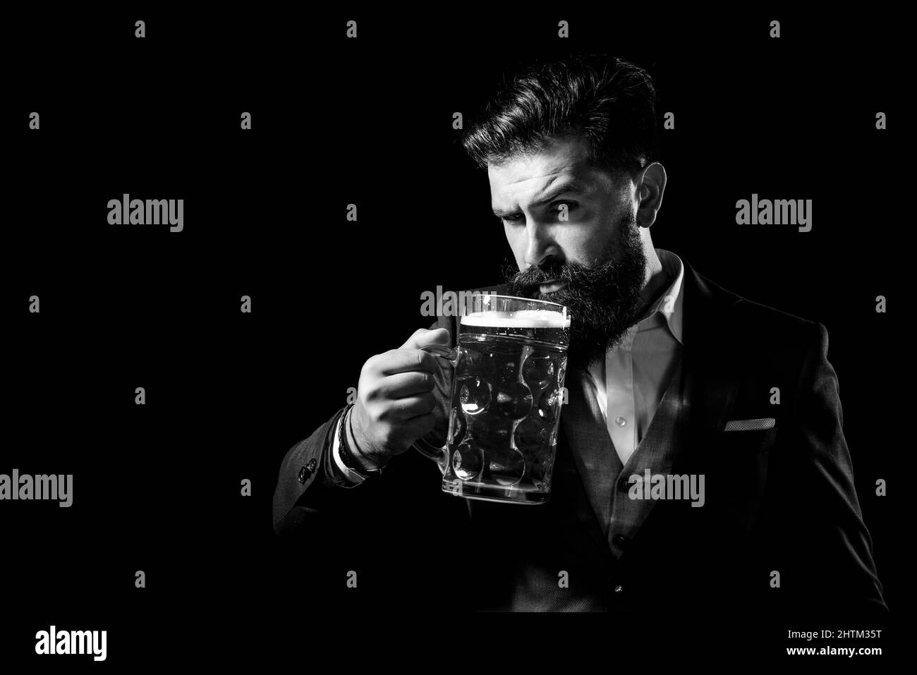 Hipster con barba e baffi in tuta bevande birra dopo la giornata di lavoro. Germania Baviera. Tempo della birra. Bel barman che tiene una pinta di birra. Foto Stock