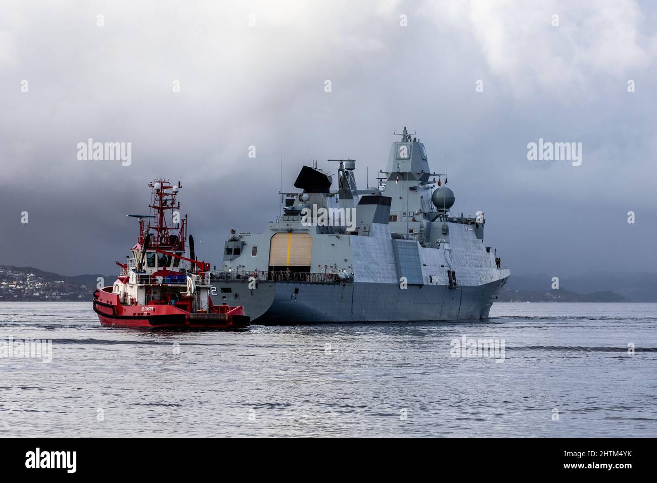 Fregata danese di classe Ver Huitfeldt F362 HDMS Peter Willemoes a Byfjorden, al largo del porto di Bergen, Norvegia. Tugboat BB Coaster nelle vicinanze. Un scuro, piovoso un Foto Stock