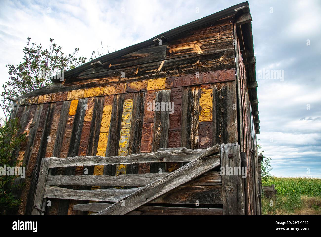 Vecchio fienile in legno intemperiato con antiche targhe Wyoming inchiodate al muro per la protezione e la decorazione con la vecchia porta di corallo al muro Foto Stock