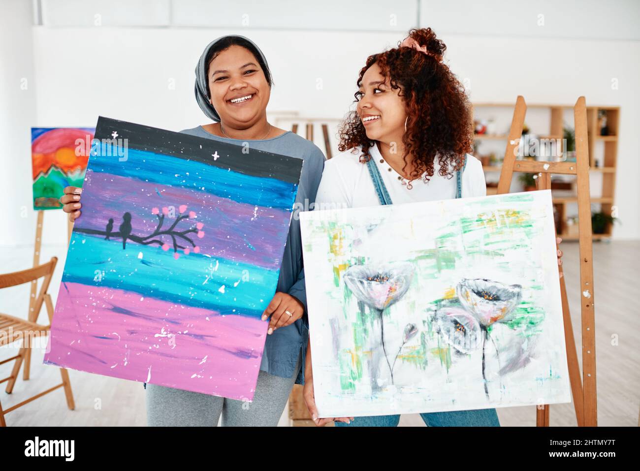 Siamo orgogliosi artisti. Ritratto ritagliato di due giovani donne attraenti in piedi insieme e tenendo la loro opera dopo una classe d'arte in studio. Foto Stock