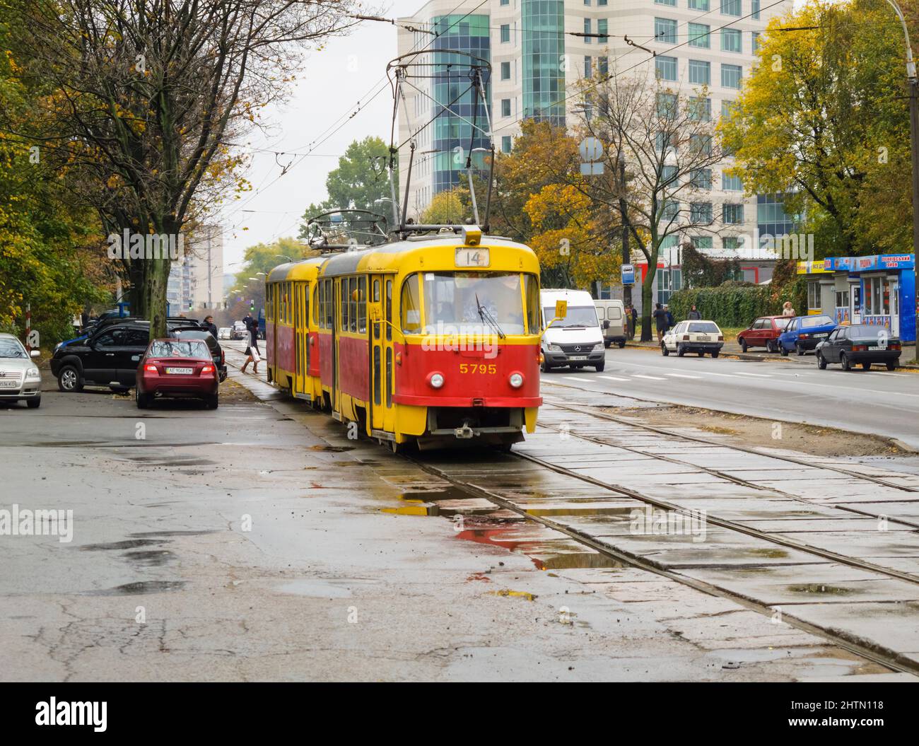 Trasporti pubblici a Kiev (Kiev), capitale dell'Ucraina: Un tram rosso e giallo (tram) in una strada nel centro della città in una giornata opaca e umida Foto Stock