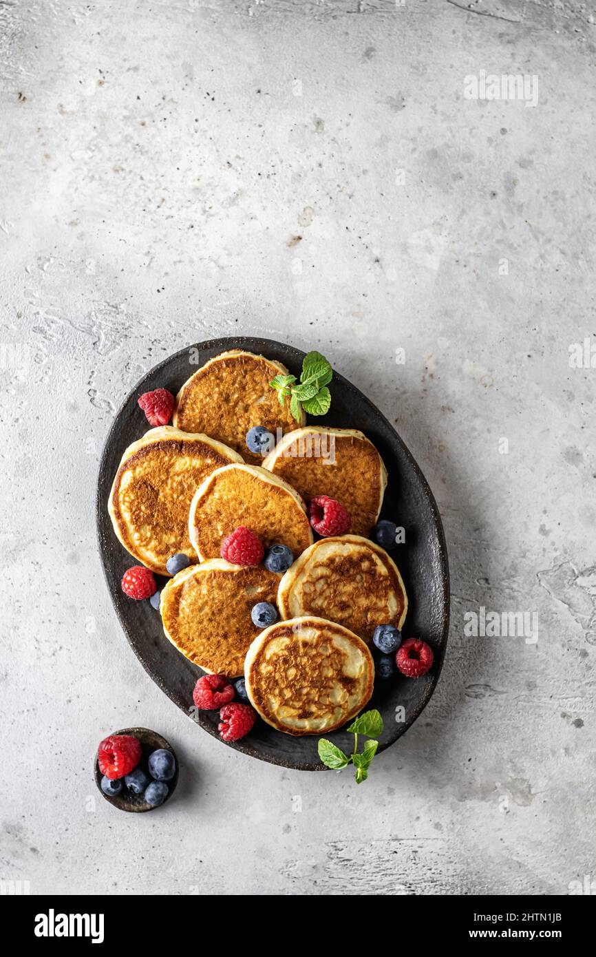 Pancake in piastra di ceramica con frutti di bosco, foglie di menta e barca con sugo di carne, vista dall'alto Foto Stock