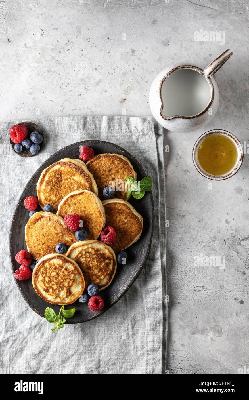 Pancake in piastra di ceramica con frutti di bosco, foglie di menta, barche con sugo di carne su tovagliolo di lino, vista dall'alto Foto Stock