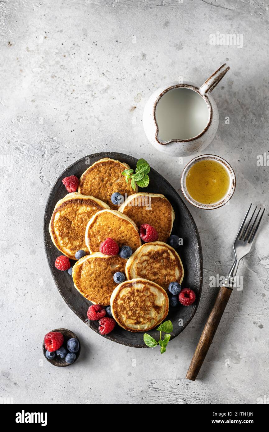 Pancake in piastra di ceramica con frutti di bosco, foglie di menta, barche con sugo di carne e forchetta, vista dall'alto Foto Stock