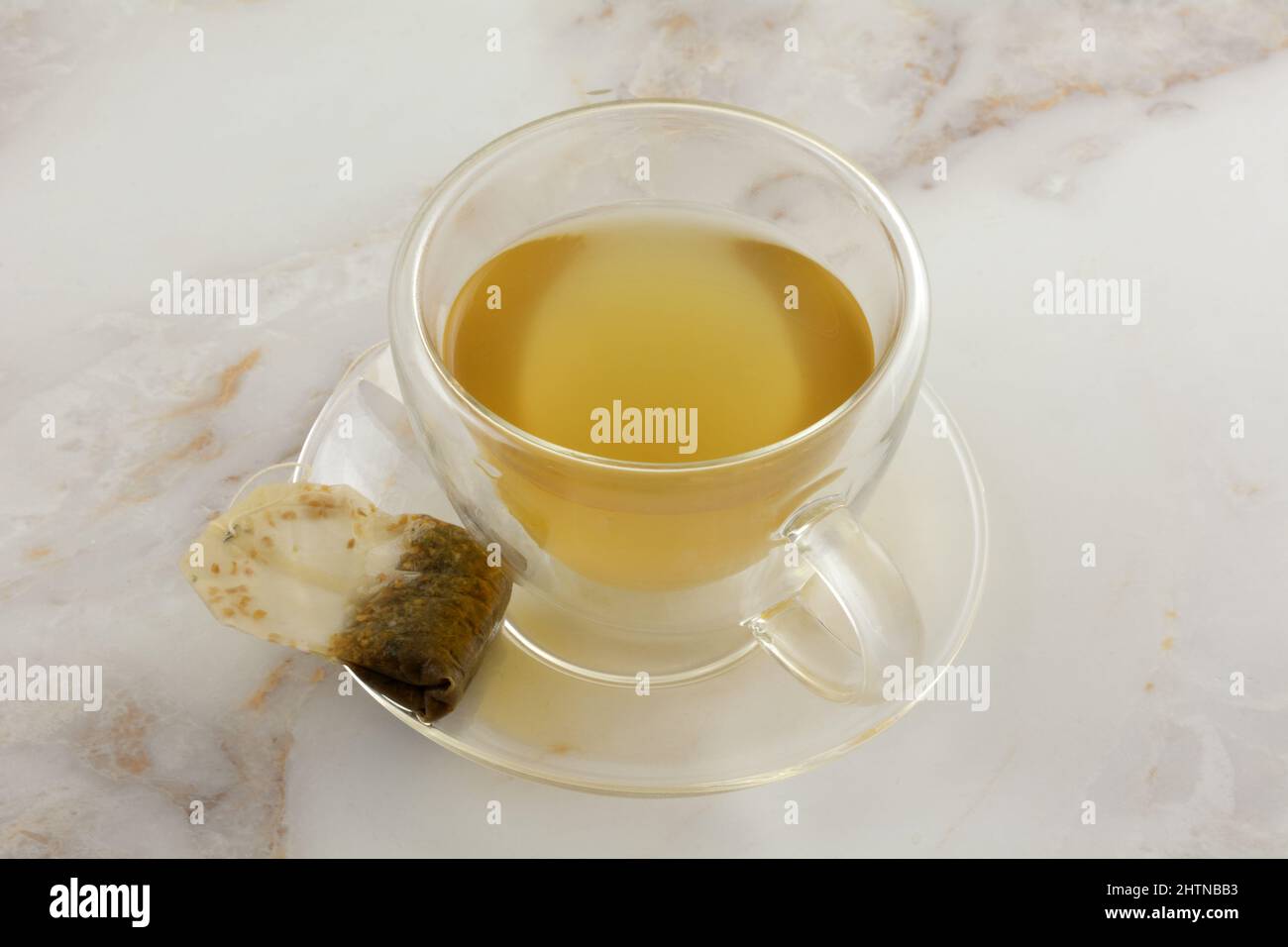 Tè allo zenzero al limone in teacup di vetro isolato con teabag usato sul piatto Foto Stock