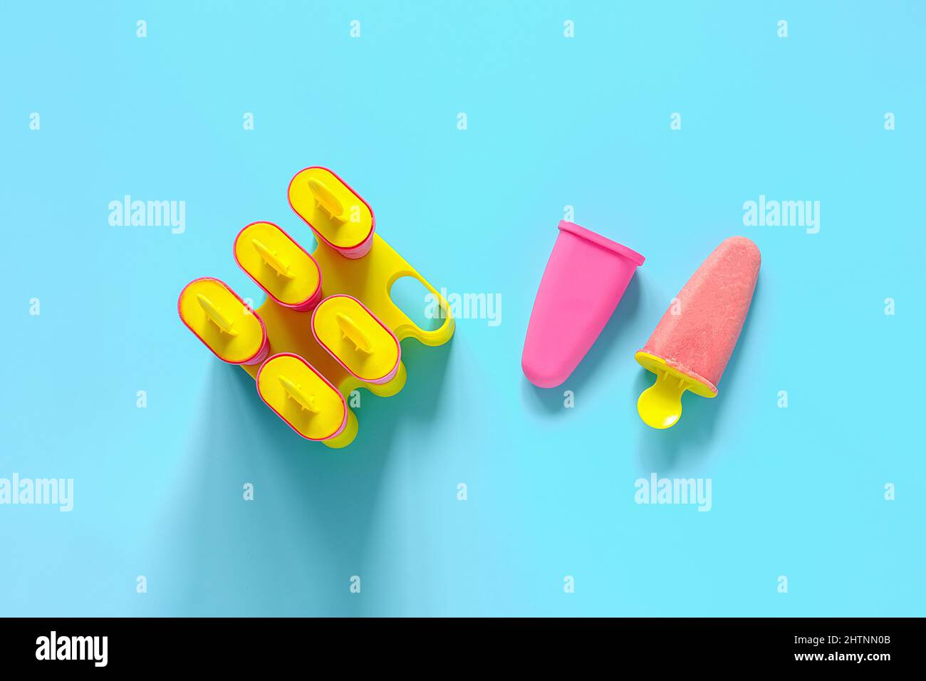 Popsicles fatti in casa. Gelato alla fragola naturale in stampi di plastica su sfondo blu con spazio copia. Vista dall'alto modello di disposizione piatta per il. Foto Stock