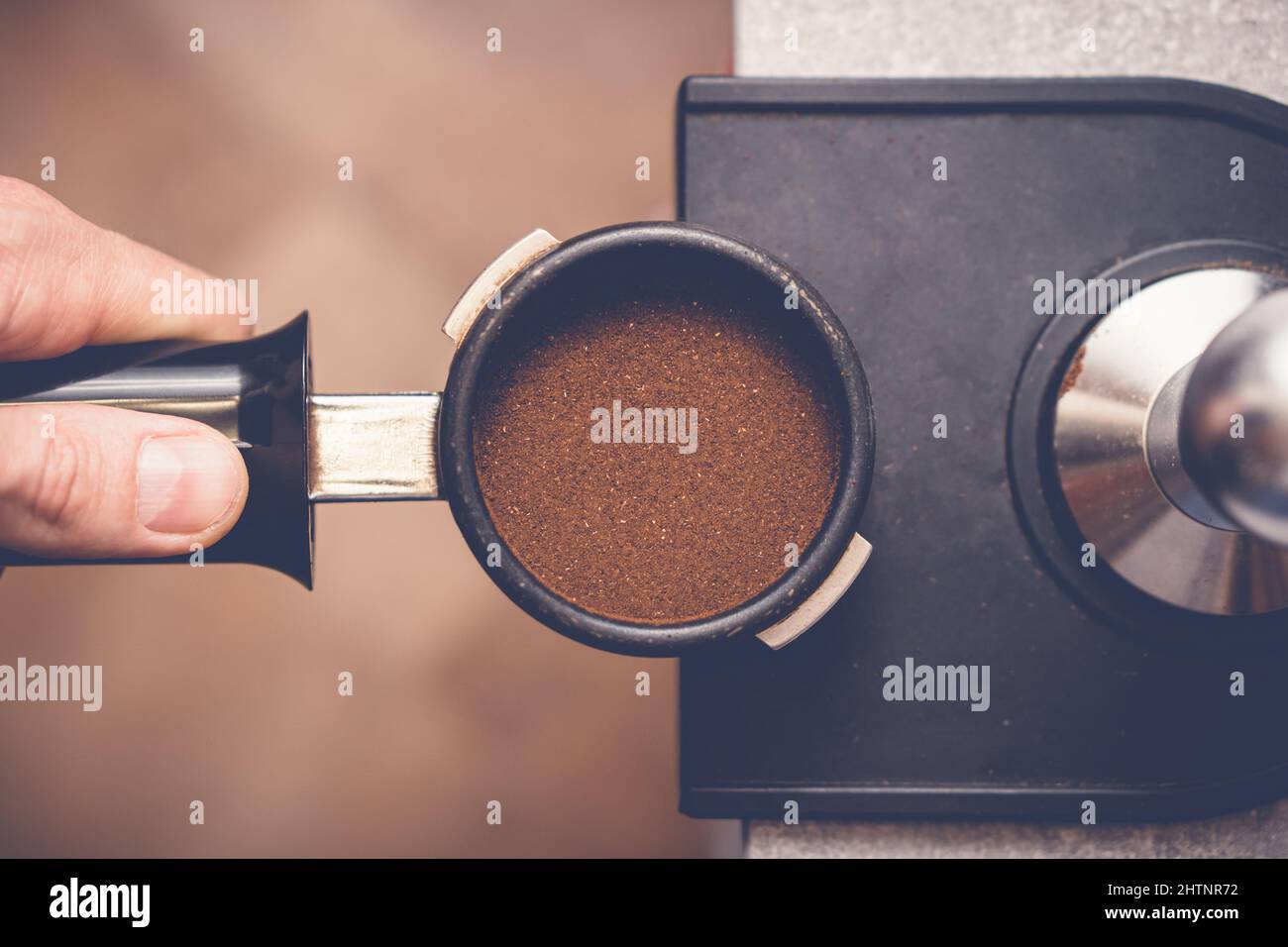 Barista manomissione caffè in portafiltro con manomissione. Primo piano del processo di preparazione del caffè fresco Foto Stock