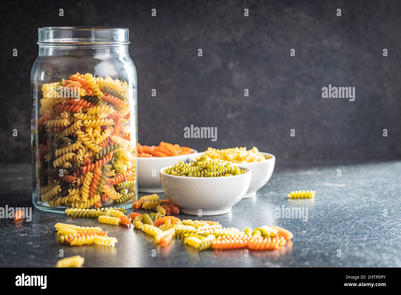 Fusilli a tre colori. Pasta cruda italiana colorata in vaso. Foto Stock