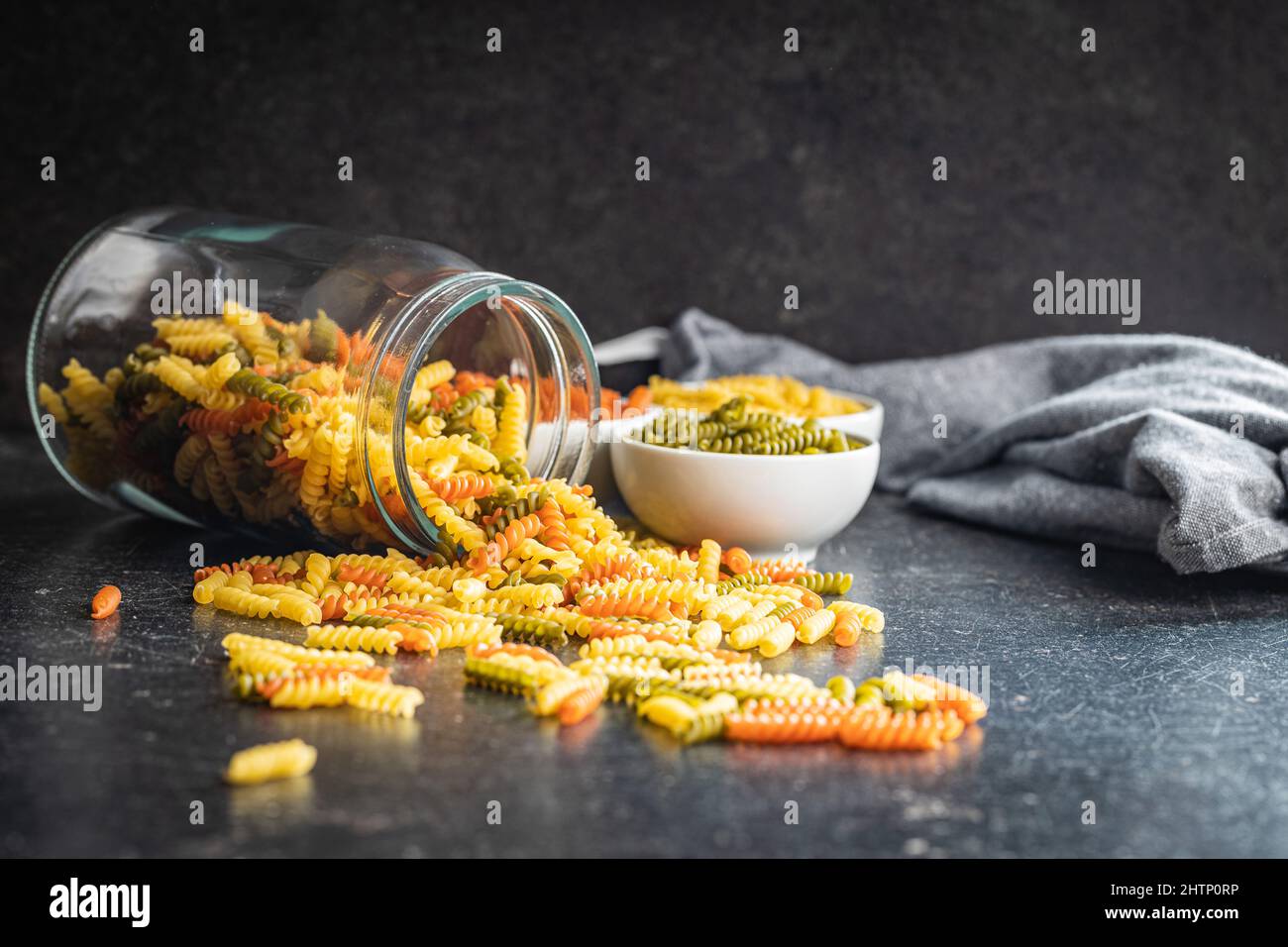 Fusilli a tre colori. Pasta italiana cruda colorata sul tavolo da cucina. Foto Stock