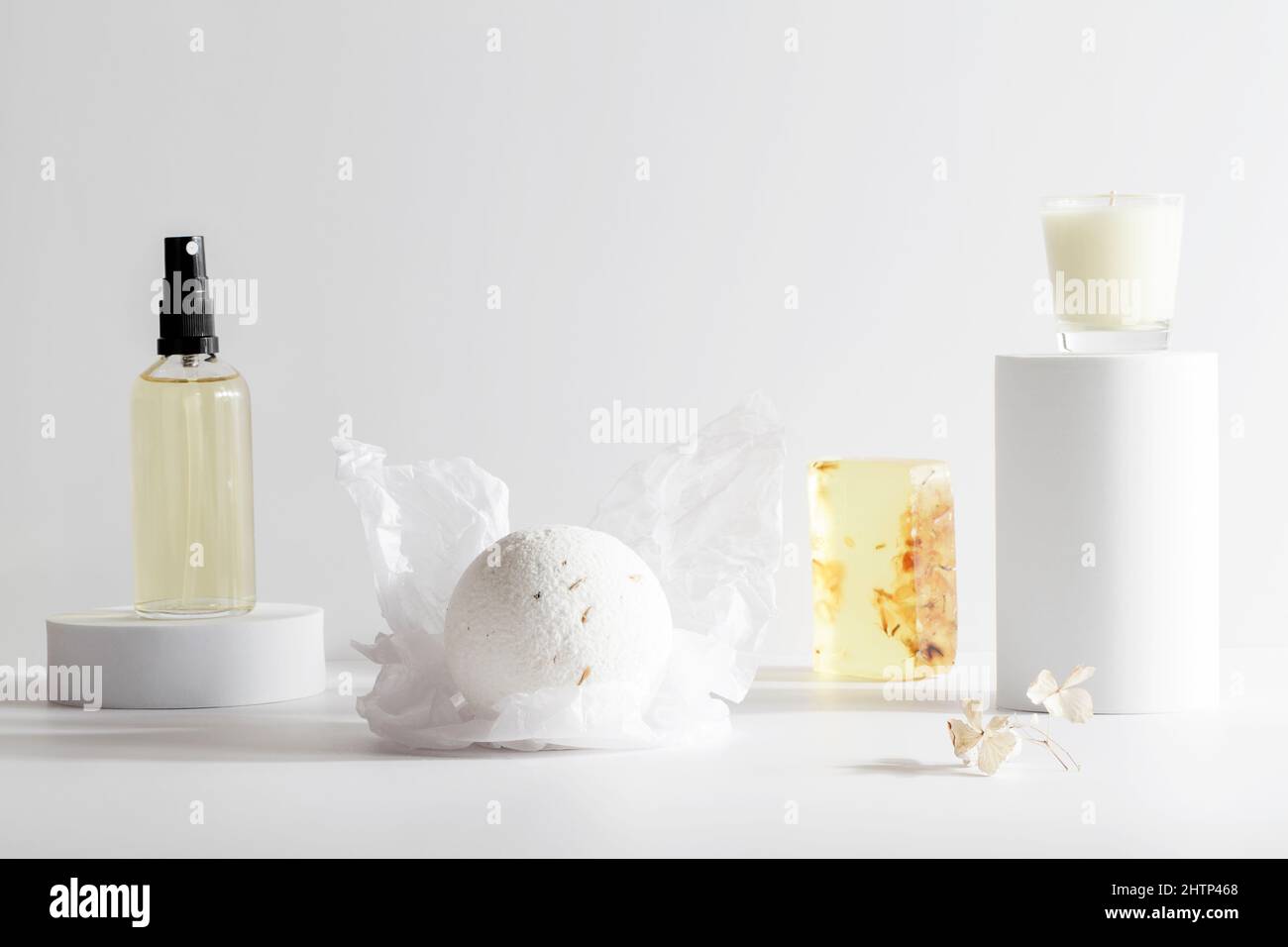 bomba da bagno, sapone fatto a mano, olio e candela sul podio su sfondo bianco. Natura morta, relax, concetto di benessere. Composizione per salone spa. Spazio copia Foto Stock