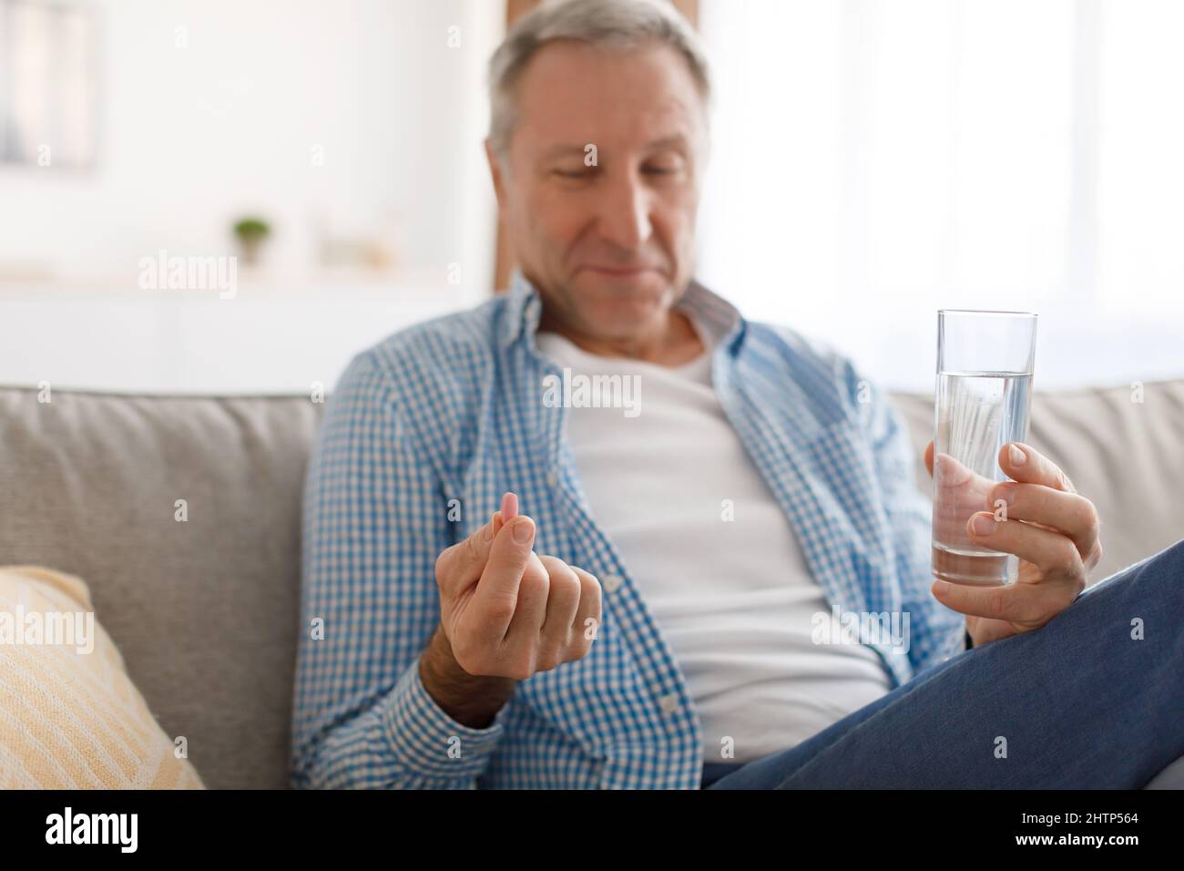 Uomo maturo che prende le pillole che tengono un bicchiere d'acqua Foto Stock