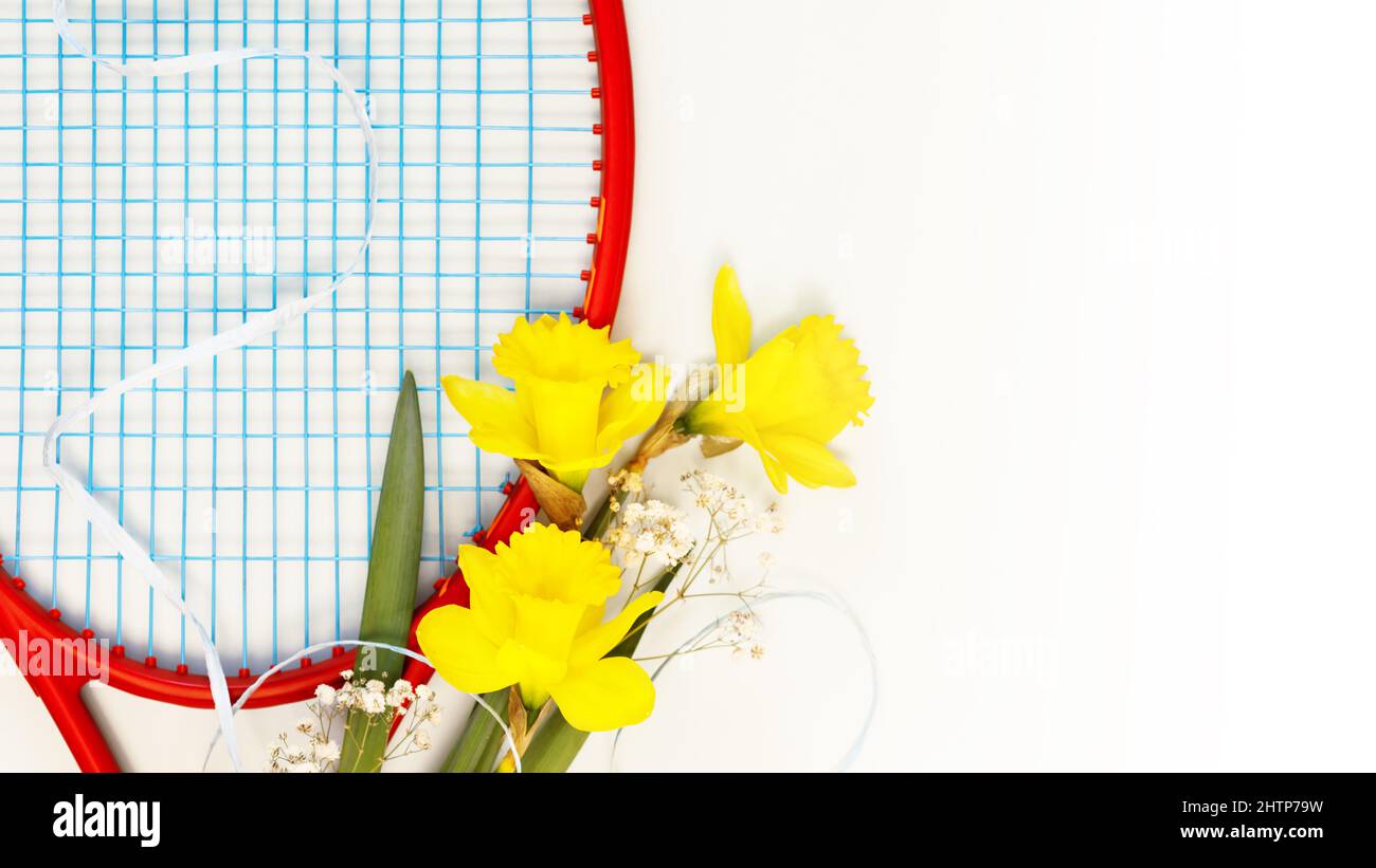 Tennis. Composizione sportiva per le vacanze con racchetta da tennis con bouquet di narcisi su sfondo bianco con spazio copia. Sport e stile di vita sano. Il Foto Stock