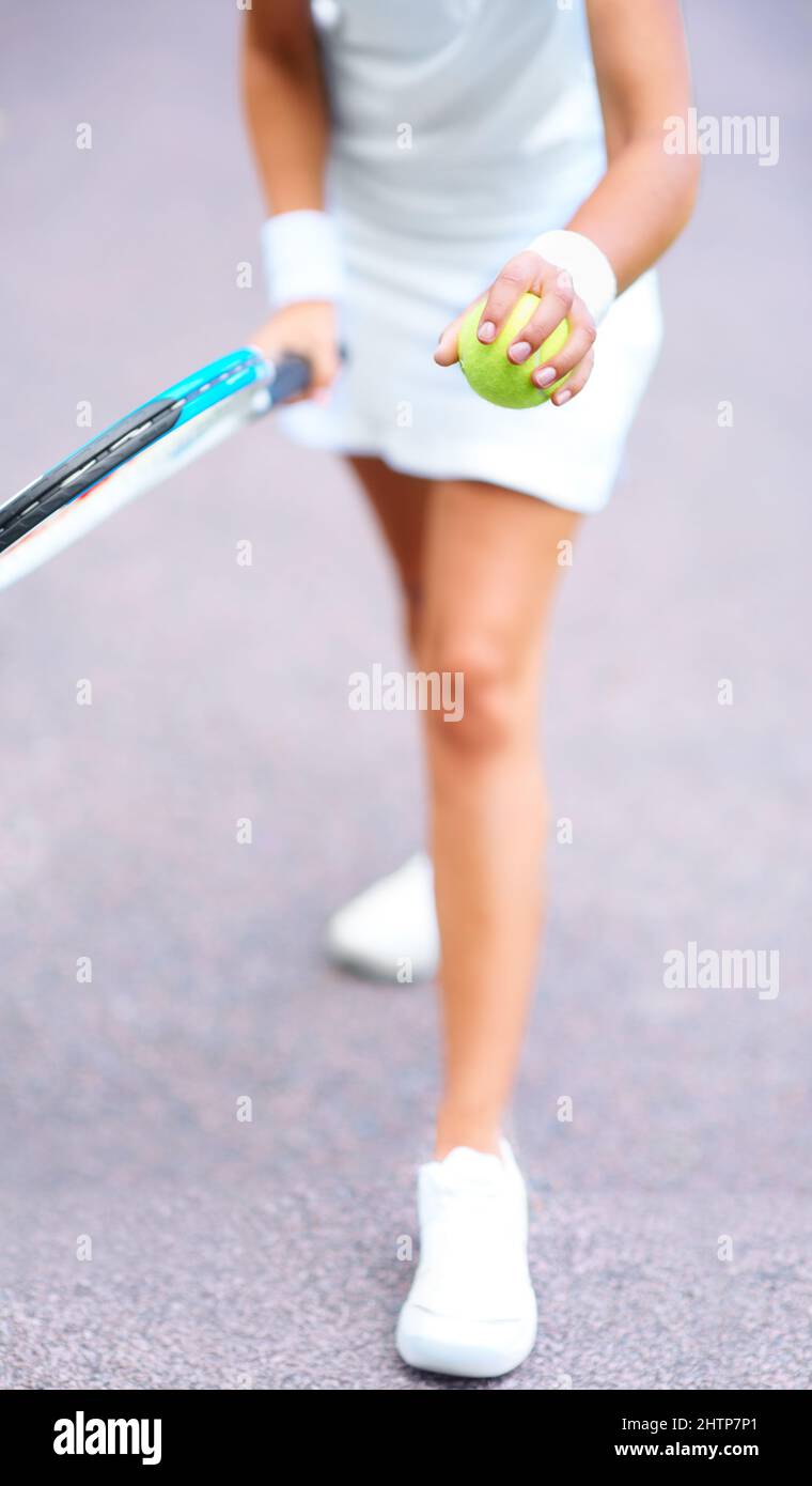 Preparatevi per il servizio. Vista ritagliata di una giovane tennista femminile che si prepara a servire la palla. Foto Stock