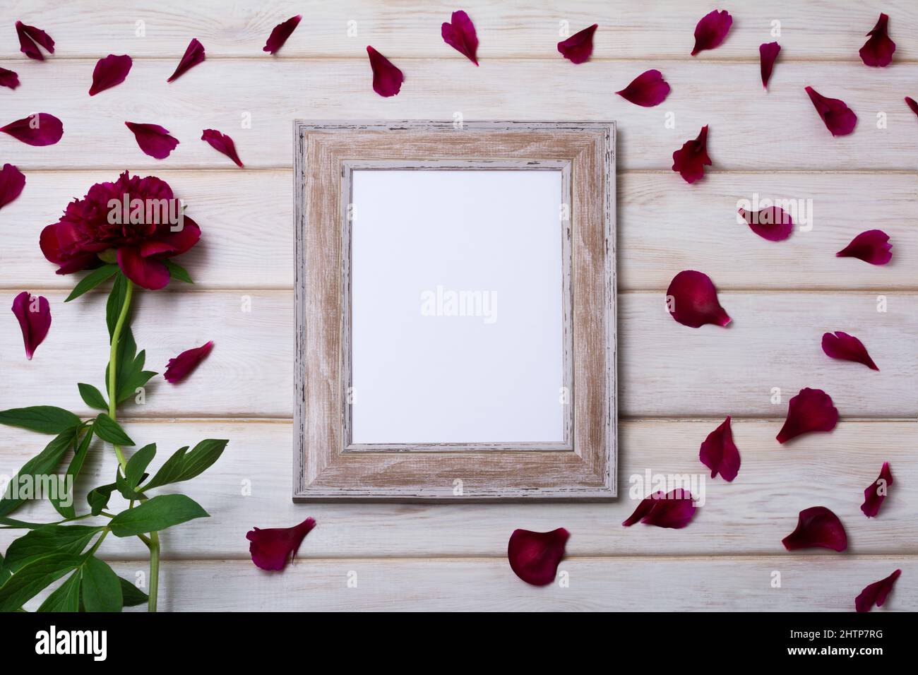 Mockup in legno con peonia e petali di borgogna. Cornice vuota per il design della presentazione. Cornici a dima per arte moderna Foto Stock