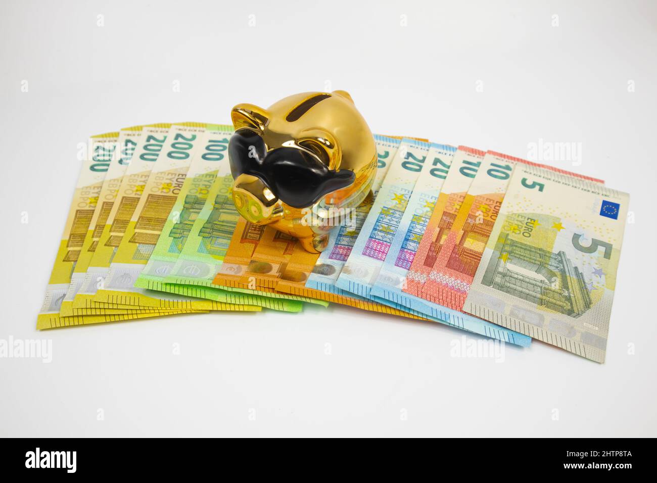 Una piggy banca di colore dorato si trova su euro moneta, su uno sfondo bianco. Foto Stock