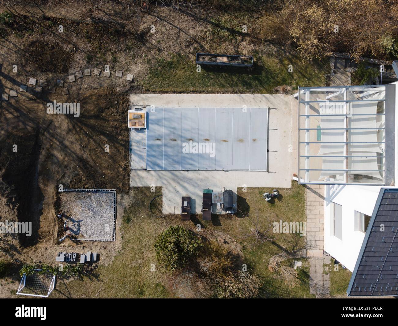 Drone volo su una piscina coperta con un tarp che è ancora in costruzione in un giardino Foto Stock