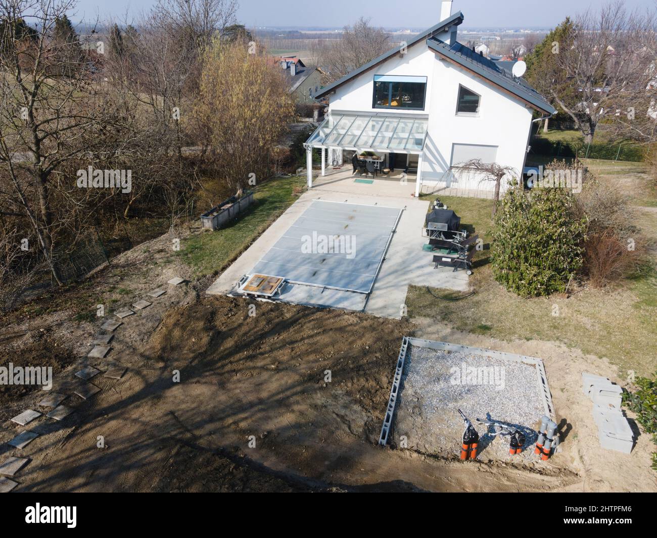 Drone volo su una piscina coperta con un tarp che è ancora in costruzione in un giardino Foto Stock