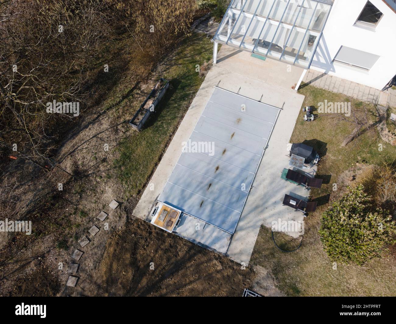 Drone volo su una piscina coperta con un tarp che è ancora in costruzione in un giardino Foto Stock