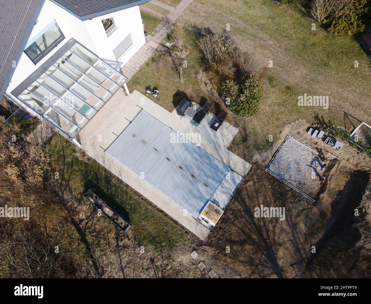 Drone volo su una piscina coperta con un tarp che è ancora in costruzione in un giardino Foto Stock