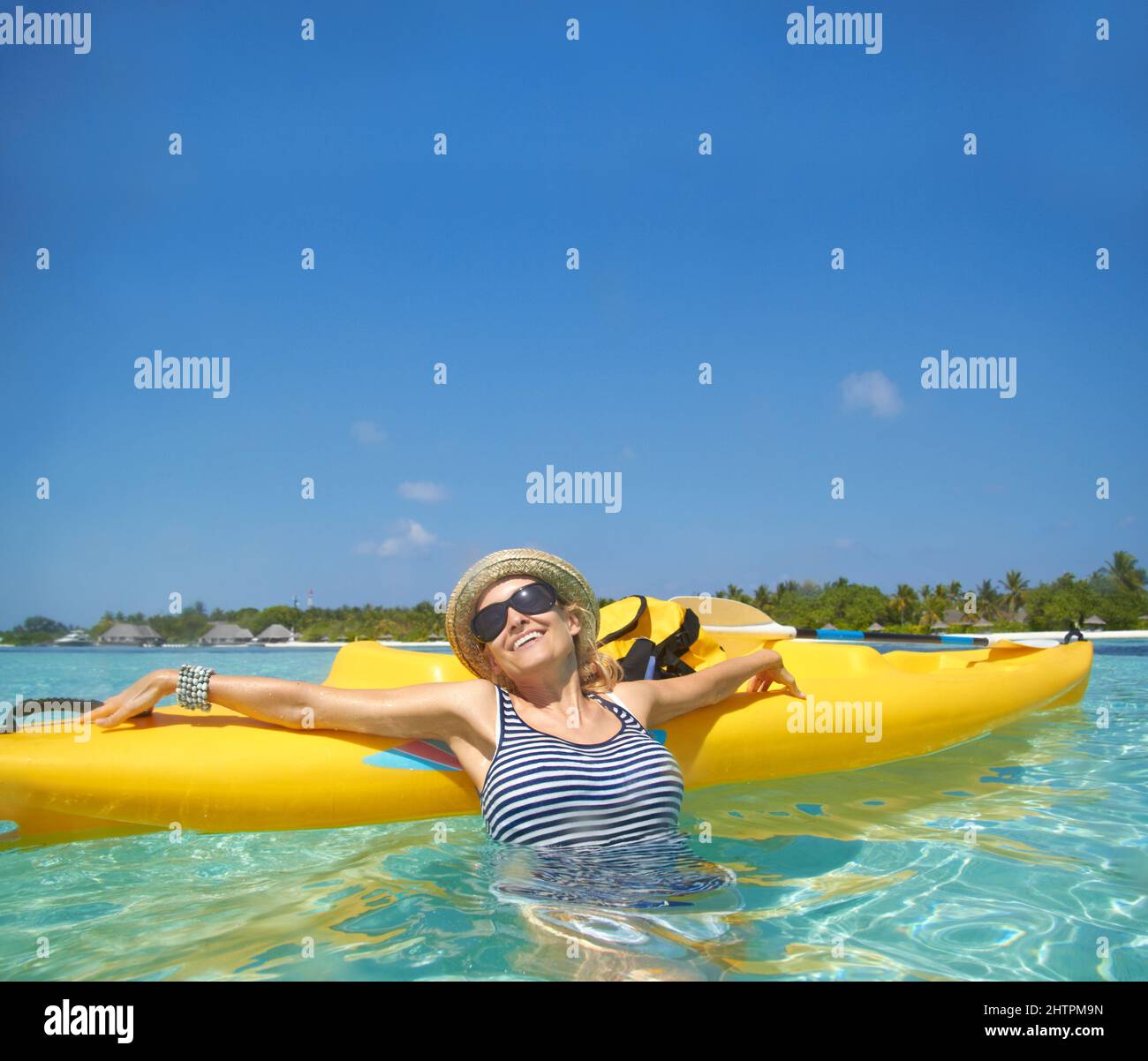 La vacanza più rilassante. Una bella giovane donna che si rilassa in un oceano tropicale con la sua barca. Foto Stock