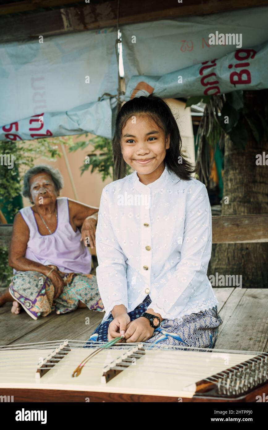 Bella ragazza thailandese che suona il tradizionale strumento di musica Khim vicino alla nonna Foto Stock