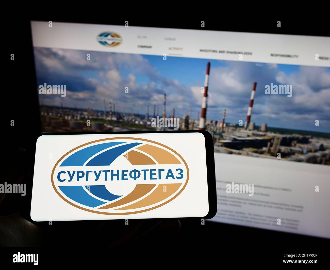 Persona che tiene il telefono cellulare con il logo della società russa di gas naturale Surgutneftegas sullo schermo di fronte alla pagina web. Mettere a fuoco sul display del telefono. Foto Stock