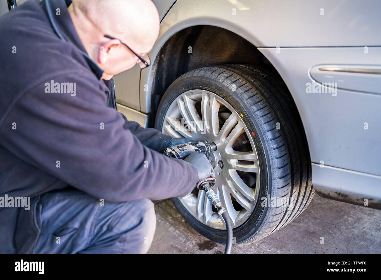 Officina del garage per pneumatici. Il personale del garage può rimontare una ruota su un'auto utilizzando una chiave pneumatica. Foto Stock
