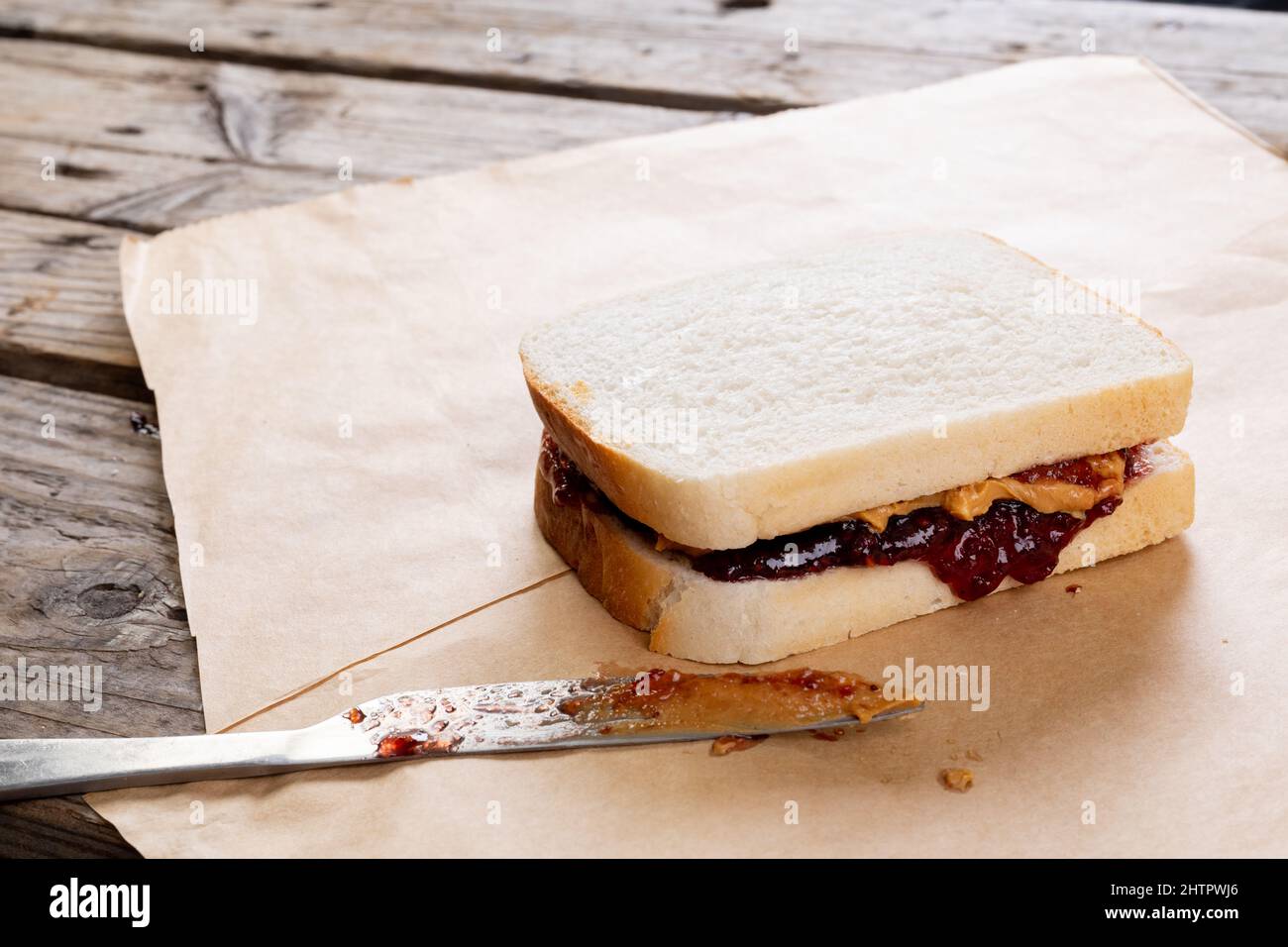 Sandwich di burro di arachidi e gelatina su carta marrone con coltello da tavolo a tavola Foto Stock