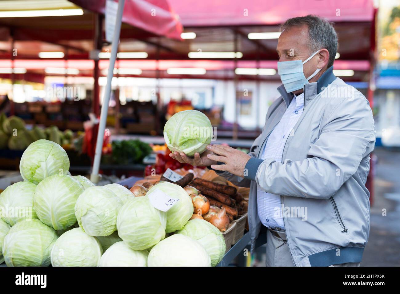 Uomo in maschera acquistare cavolo nel mercato Foto Stock