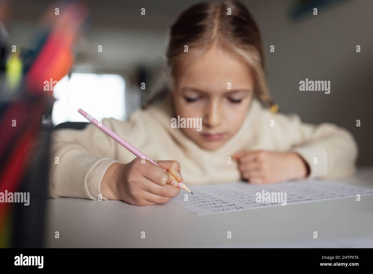 Capretto caucasico che studia in linea nel paese e nella scrittura. Scuola piuttosto seria che studia matematica di lavoro durante la quarantena di coronavirus covid-19 e sociale Foto Stock