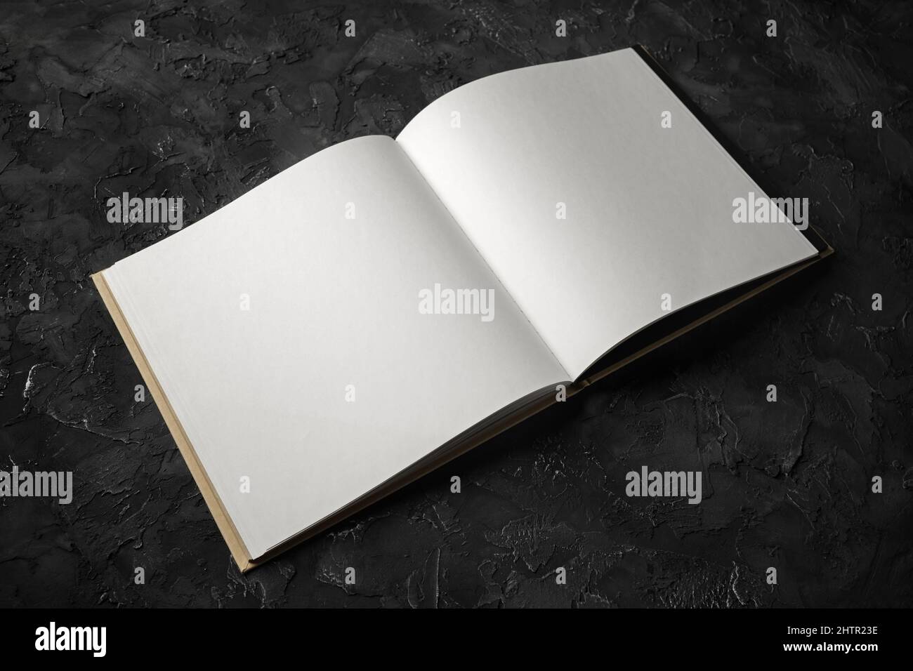 Libro vuoto aperto su sfondo di pietra nera. Foto Stock