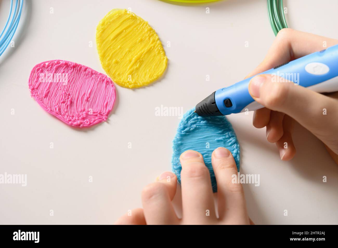 Il bambino disegna 3D Pen. Filamenti colorati in plastica arcobaleno con per 3D penne su sfondo bianco. Giocattolo per bambini. Primo piano. Foto Stock