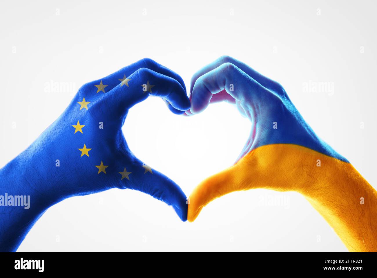 Concetto di sostegno dall'Unione europea all'Ucraina con le mani dipinte di ogni bandiera che formano un cuore su sfondo bianco Foto Stock